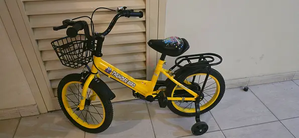 Yellow kids bicycle with training wheels and basket - good condition