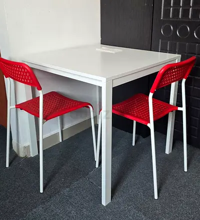 Compact white dining table with 4 red and white chairs - good condition