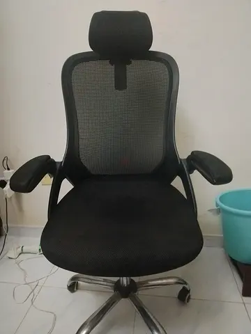 black ergonomic high-back mesh office chair featuring a padded headrest and flip-up armrests