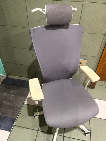 Ergonomic grey office chair with adjustable headrest and armrests