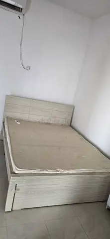 Queen-size wooden bed frame with headboard and mattress