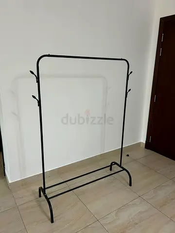 Black freestanding clothes rack with hooks.