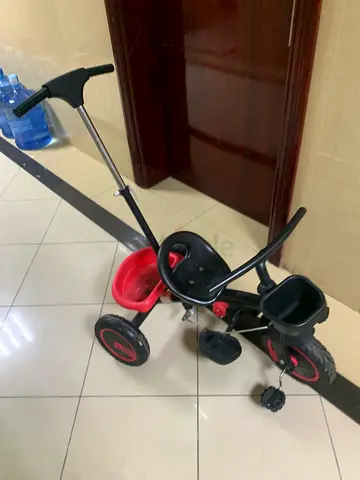 Red and black toddler tricycle with parent push handle - good condition