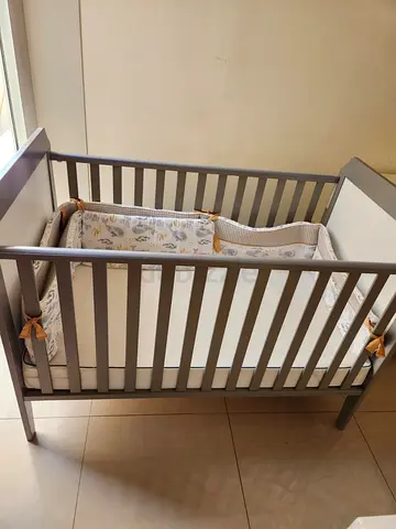 Grey wooden baby crib with mattress and bumper - good condition