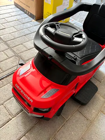 Red Defender ride-on kids car with steering wheel and footrest