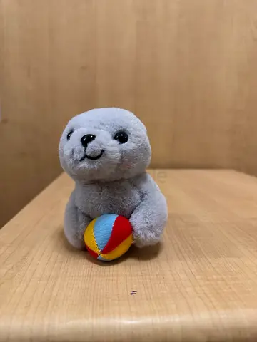 Small grey plush seal toy with colorful ball