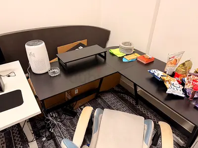 L-shaped black office desk with monitor stand and storage