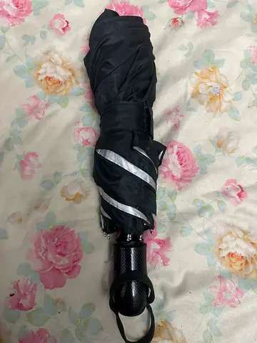 Compact black folding umbrella with reflective strip.