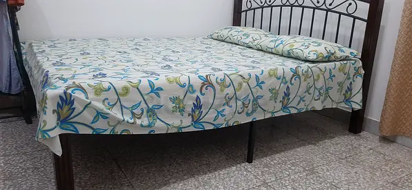 Used metal frame double bed with floral bedsheet — good condition