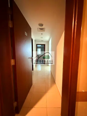 شقة واسعة للإيجار في "أورينت تاور" (Orient Tower)، تتكون من غرفة نوم واحدة وصالة (1 BHK)، مع موقف سيارات وحمامين وشرفة (بإطلالة مفتوحة على الحديقة)، ب