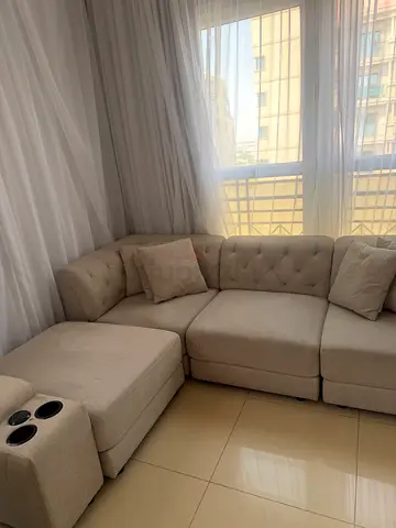 Light grey L-shaped fabric sofa with cup holders
