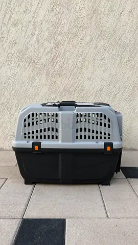 Hard-sided plastic pet carrier with a secure front wire door and side latches.