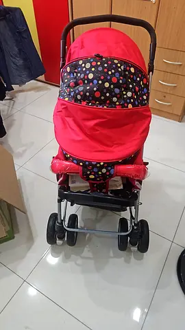 Red baby stroller with colorful polka-dot canopy - good condition