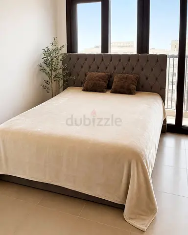 A soft beige bedspread for a king‑size bed