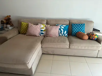Beige L-shaped 4-seater Sofa with 4 small pillows.