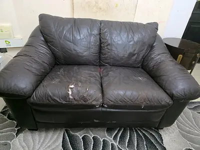 Worn dark brown 2-seater leather sofa - needs repair