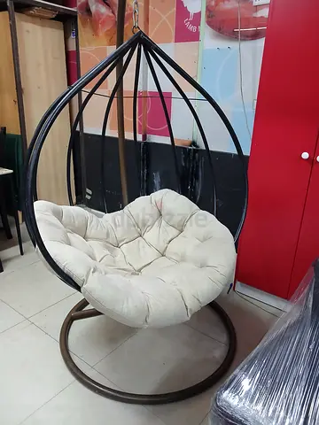 Black metal hanging swivel chair with cream cushion