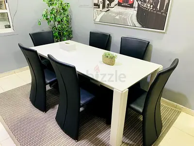White dining table with 6 black leather chairs - good condition