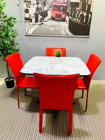 Square dining table with white marble top and 4 red chairs