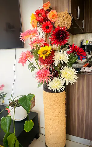 Tall decorative faux flower arrangement in woven vase with lights
