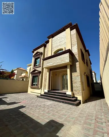 Villa for sale in Ajman Al Rawda 1 area Prime location Stone facade Close to amenities Near Sheikh Ammar bin Humaid Street Two-story villa Features 6 master bedrooms Majlis (sitting room) Two living a