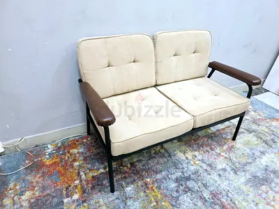Two-seater beige fabric sofa with wooden arms and metal frame