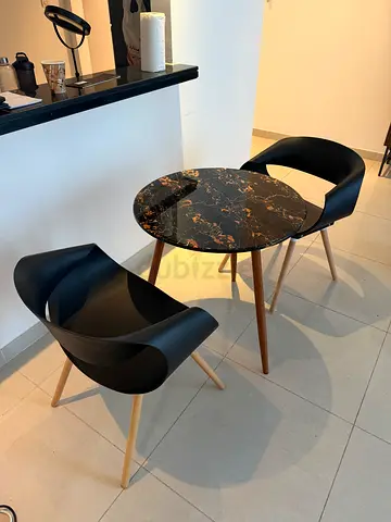 Small round faux-marble side table with two modern black chairs