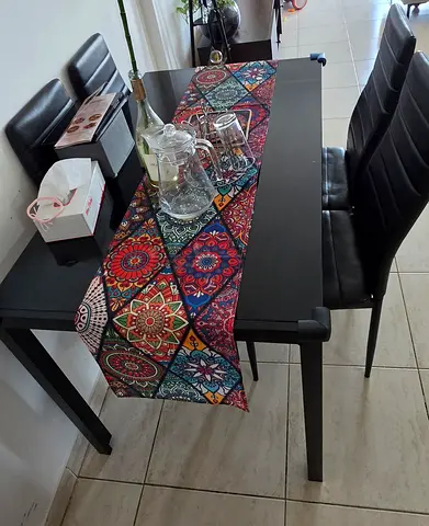 Black dining table with 4 faux-leather chairs and colorful runner - good condition