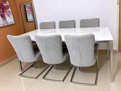 Modern white plywood top dining table with 6 grey upholstered cantilever chairs