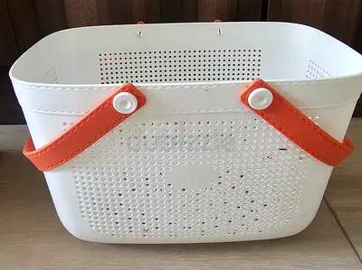 White plastic storage basket with orange handles, paddu maker, oil bottle