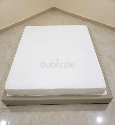 Plain white Mattres stand having tires down (movable easily) with beige border along with mattress