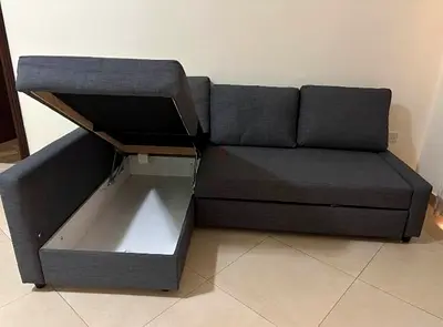 L-shaped grey fabric sofa with storage and pull-out bed - good condition