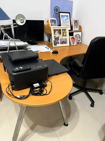 L-shaped wooden office desk with matching round side table and swivel chair