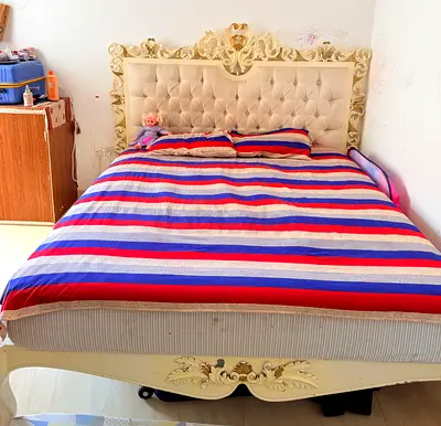Ornate carved wooden double bed with tufted headboard