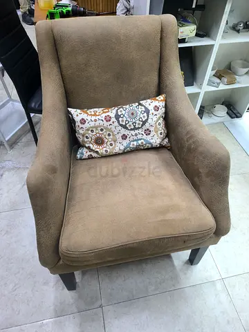 Comfortable single armchair in beige with decorative cushion