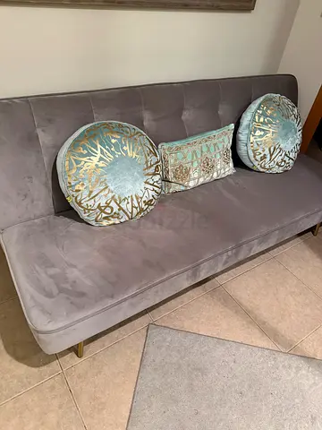 Grey velvet 3-seater sofa bed with decorative cushions