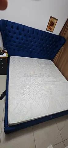 Blue tufted king-size bed frame with mattress