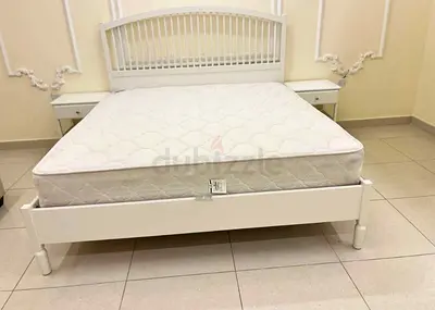 White wooden double bed frame with mattress and bedside tables