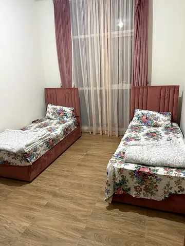 Pair of single beds with upholstered headboards and floral mattresses and curtain