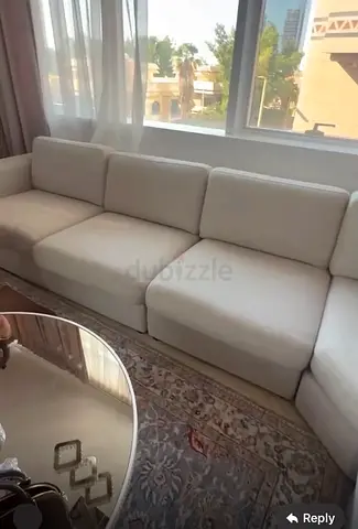 Large L-shaped beige fabric sectional sofa with cushions - good condition