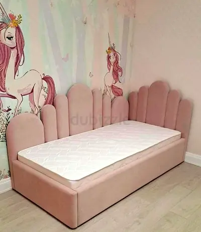 Pink upholstered single daybed with scalloped headboard — kids bedroom