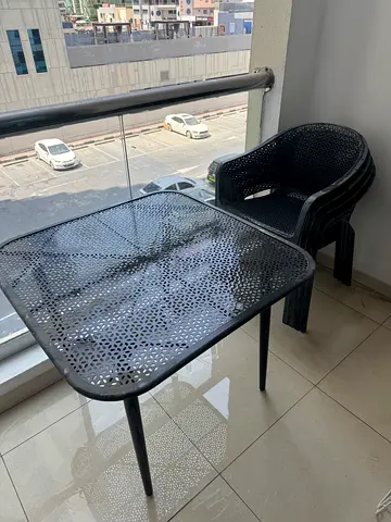 Outdoor metal patio table with stackable plastic chairs - good condition