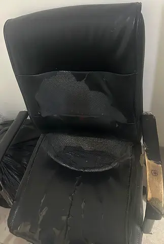 Used black office chair with worn upholstery and armrests