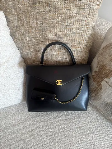 Classic black Chanel-style leather handbag with gold chain detail
