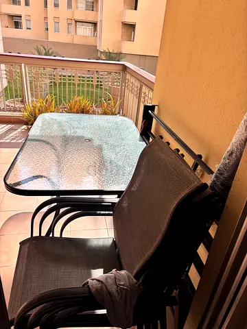 Glass-top outdoor dining table with 4 stackable chairs - good condition