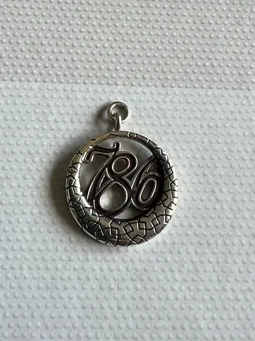 Silver circular pendant charm with decorative number/letter detail
