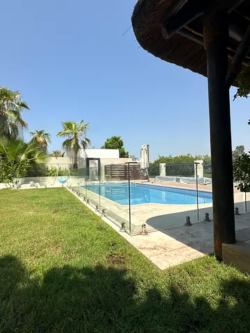 Private villa poolside area with glass balustrade and lawn — reusable setup