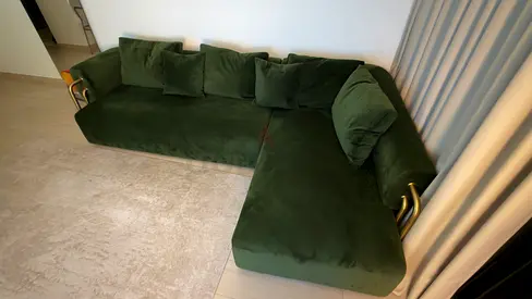 Green L-shaped velvet sofa with gold accents - good condition