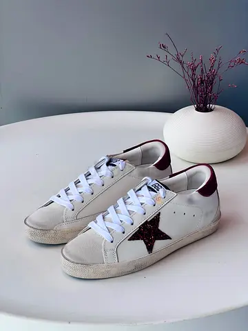 White low-top sneakers with burgundy star detail, size not specified