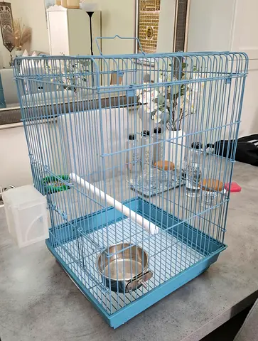 Light blue metal bird cage with perch and feeding bowls